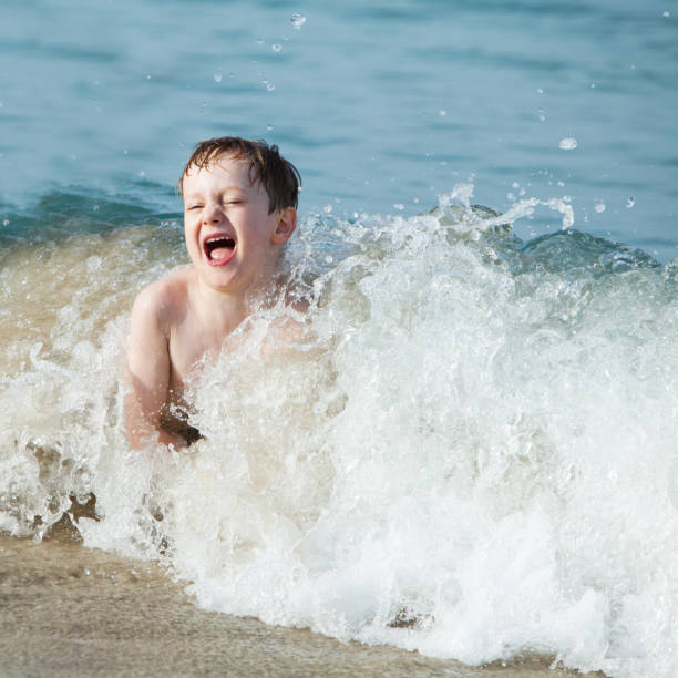 istock Little boy playing and splashing in sea waves 1317997363