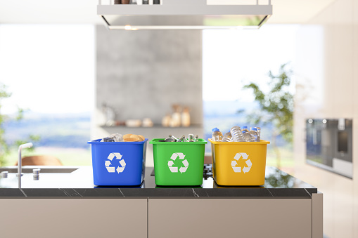 Contenedores de reciclaje en la isla de la cocina con fondo de cocina borrosa photo