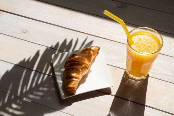 Croissant and orange juice on the wooden table