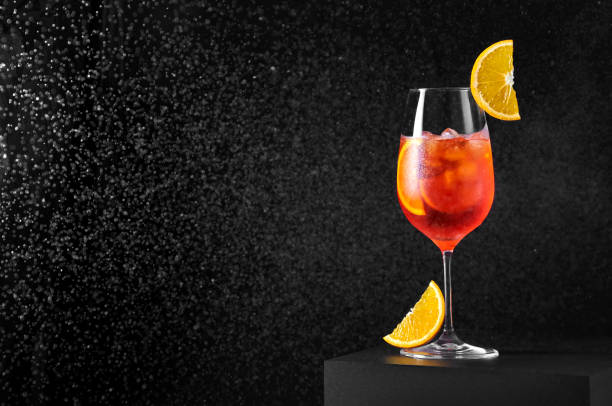 cóctel aperol spritz en copa de vino con agua salpicada sobre fondo oscuro. bebida larga y gaseosa - splashing orange fruit water fotografías e imágenes de stock