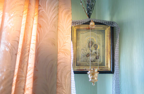 an Orthodox icon of the mother of God with the baby Jesus hangs in the corner of the room by the window stock photo