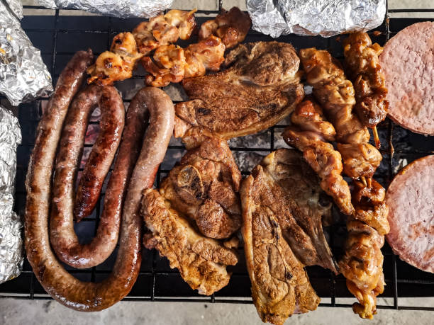 Braai Meat Braaied meat on a grid including Boerewors, lamb chops, chicken kebabs, beef burgers and garlic rolls south african braai stock pictures, royalty-free photos & images