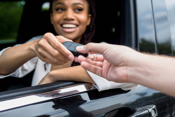 Woman smiles when she receives keys to new car The mid adult woman smiles when she is given the keys to the new car. car ownership photos stock pictures, royalty-free photos & images