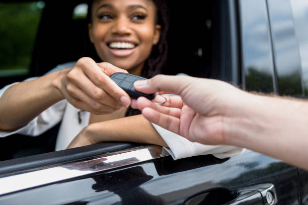 woman smiles when she receives keys to new car - valet parking imagens e fotografias de stock