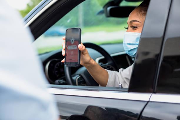 Woman shows receipt for online curbside delivery order The mid adult woman wears her protective mask to pick up the curbside delivery order.  She shows the unrecognizable man the receipt on the screen of her smart phone. curbsidepickup stock pictures, royalty-free photos & images