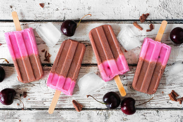 istock Chocolate and cherry popsicles in a row over a rustic white wood background 1318004476
