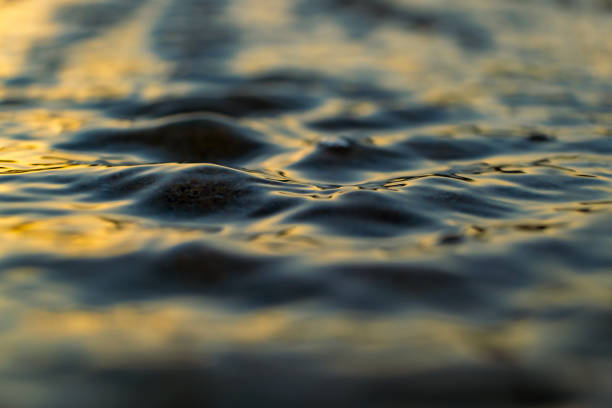 Soft sunlight, golden hour. Sea shore at sunset, close-up. storm waves. Abstract background, details blurred in bokeh. Blue, yellow, orange colors. Peace, meditation, tranquility themes