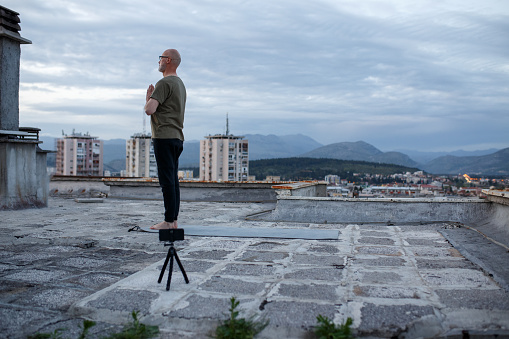 Male yoga instructor hosting an online class from rooftop.