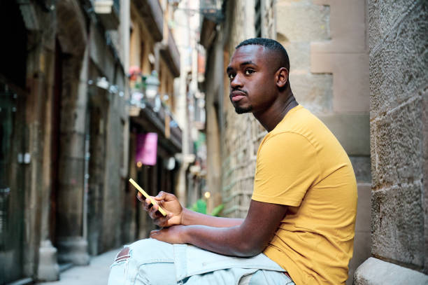 istock young black woman using smartphone while seated in old town Barcelona 1318006798