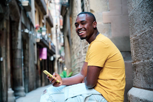 istock young african american man using smartphone and smiling at old town Barcelona 1318006801