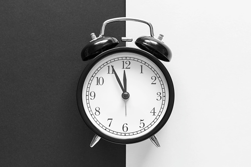 Classic alarm clock on black and white background. Time or day and night concept with copy space for text. Black and white image.