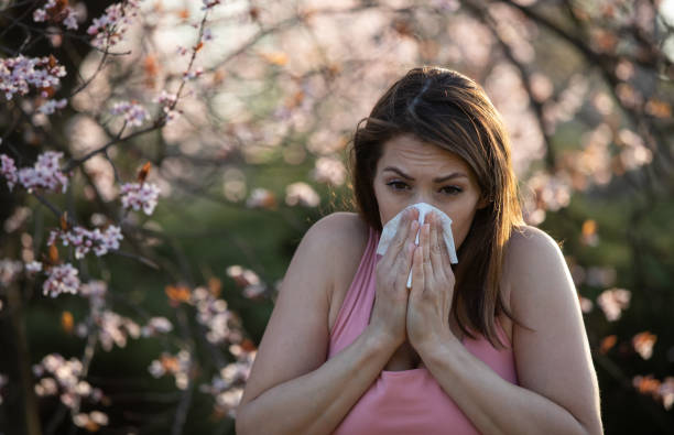 istock Woman sneezing in front of blooming tree 1318007974