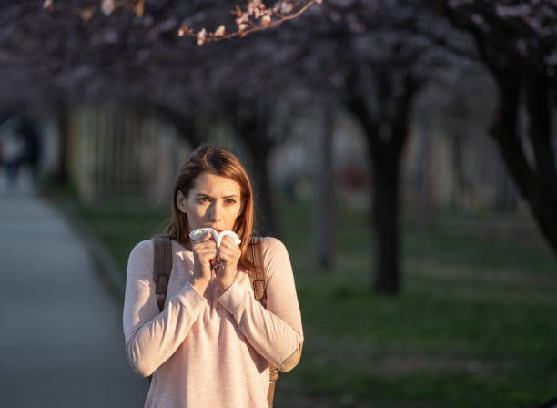 istock Woman sneezing under of blooming tree 1318007997
