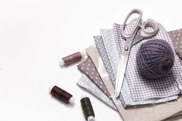 istock pastel shades of fabric with a pattern, scissors and spools of thread on a white background, a ball of gray woolen knitting threads and accessories for sewing, copy space, top view 1318010198