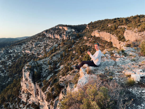 istock Young man uses mobile phone on sunny mountain ridge, sunrise 1318010349