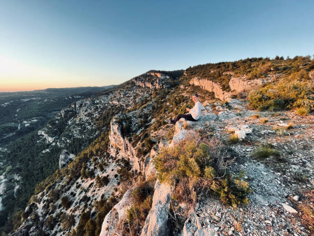 istock Young man uses mobile phone on sunny mountain ridge, sunrise 1318010350