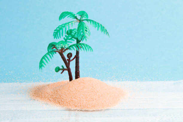 istock miniature plastic palm tree in the sand, blue background, copy space, reflection in the glass, face mask under the glass, stay home concept, canceling the journey 2020 1318011409