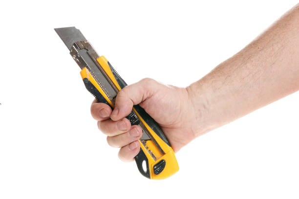 istock Hand holds a construction knife on a white background, a template for designers. Close up 1318013947