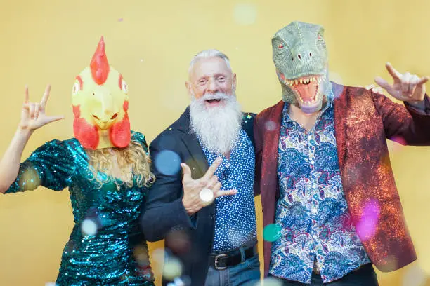 Photo of People dancing at carnival party wearing t-rex and chicken mask. Friends having fun listening rock music - Funny trend concept - Image