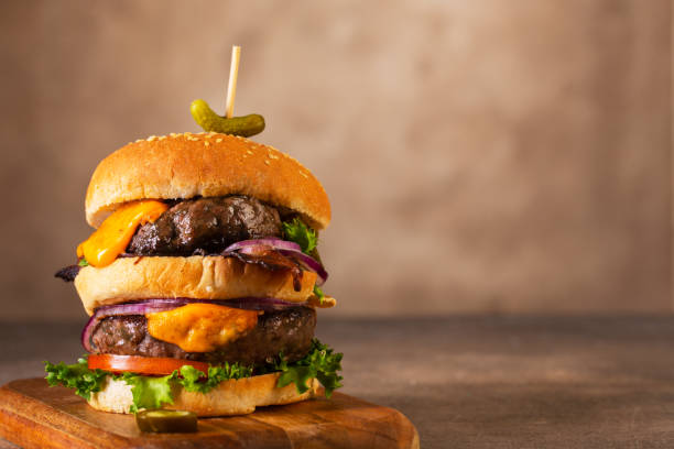 istock Home made burgers with two cutlets and melted cheese on brown background 1318016843