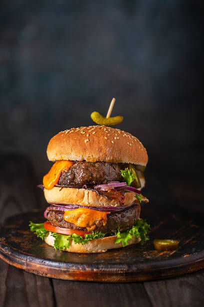istock Home made burgers with two cutlets and melted cheese on dark background 1318016869