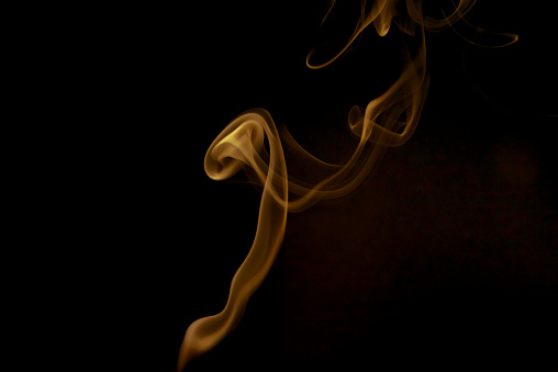 Colored smoke on black background. Yellow color.