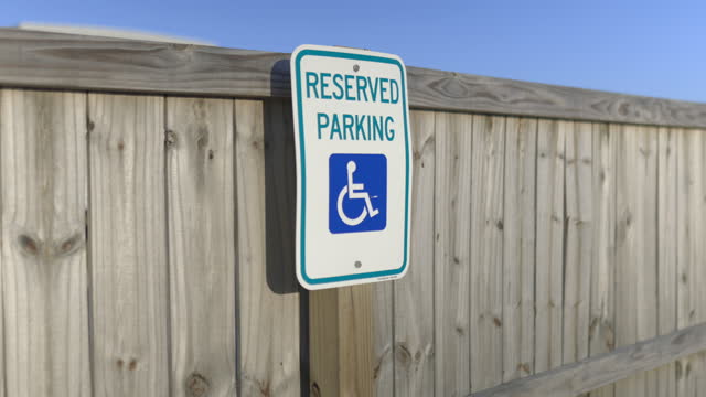 Reserved parking sign on wooden fence with blue sky as background