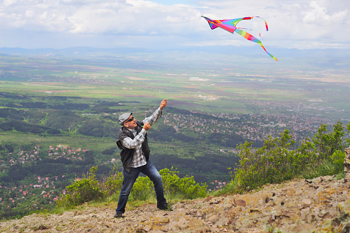 A man flying a kite on a rock field on the mountain.