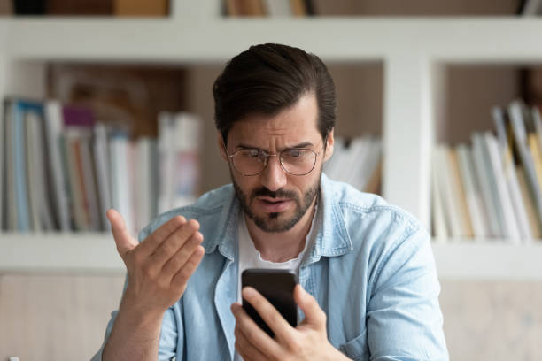 istock Close up unhappy man in glasses looking at phone screen 1318021886