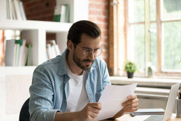 istock Satisfied businessman in glasses reading letter, working with correspondence 1318021888