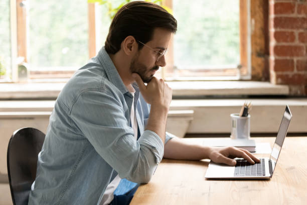 istock Side view thoughtful businessman in glasses looking at laptop screen 1318021897