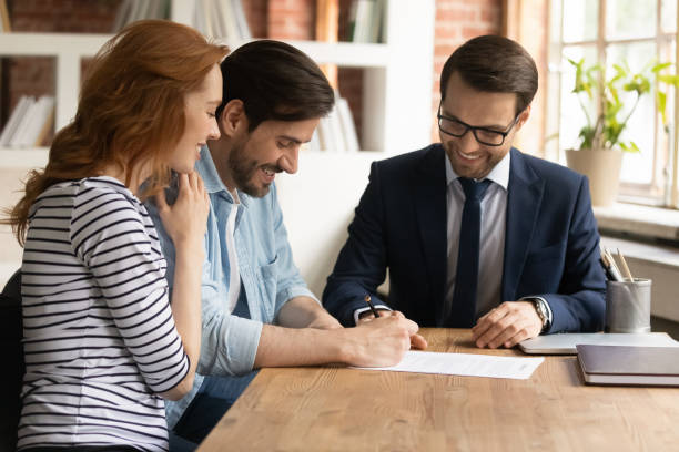 feliz pareja millennial firmando contrato con gerente en reunión - real estate agent fotografías e imágenes de stock