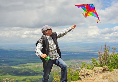 A man flying a kite on a rock field on the mountain.