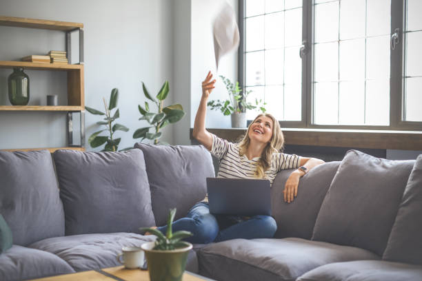 istock attractive middle aged woman sitting on the couch( laptop, paperwork, throwing) 1318029091