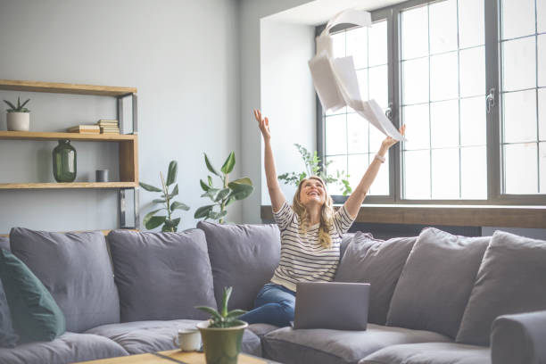 istock attractive middle aged woman sitting on the couch( laptop, paperwork, throwing) 1318029992
