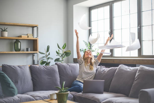 attractive middle aged woman sitting on the couch( laptop, paperwork, throwing)