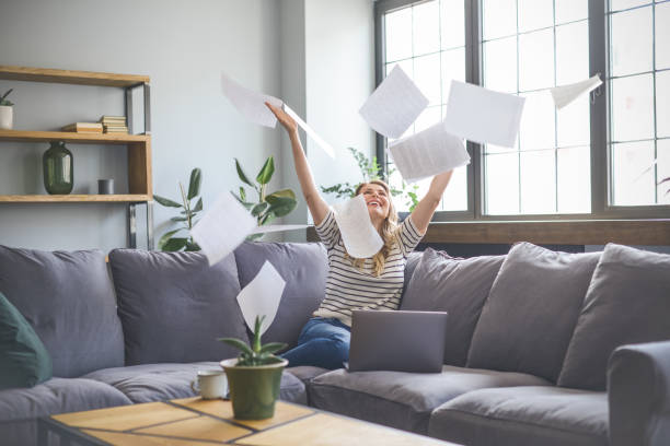 istock attractive middle aged woman sitting on the couch( laptop, paperwork, throwing) 1318031806