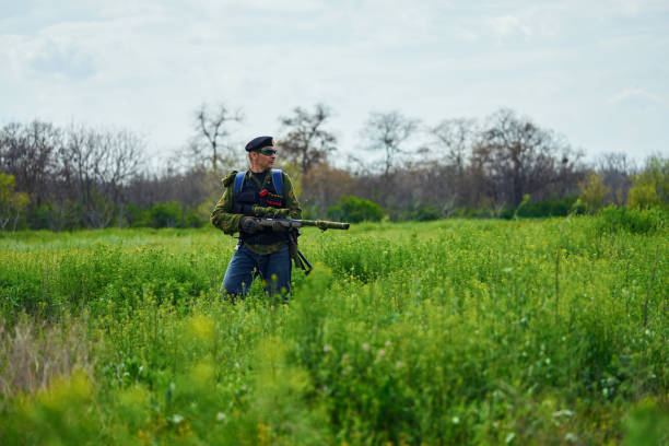 jogador de airsoft em uniforme militar camuflado tem um rifle em suas mãos - conciliator - fotografias e filmes do acervo