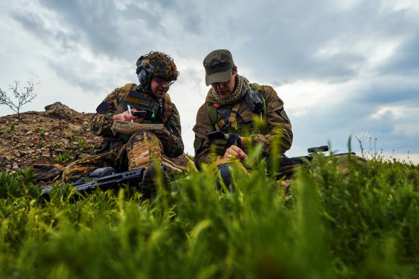 солдаты с оружием сидят на земле и смотрят на карту - hunting two people camouflage rifle стоковые фото и изображения