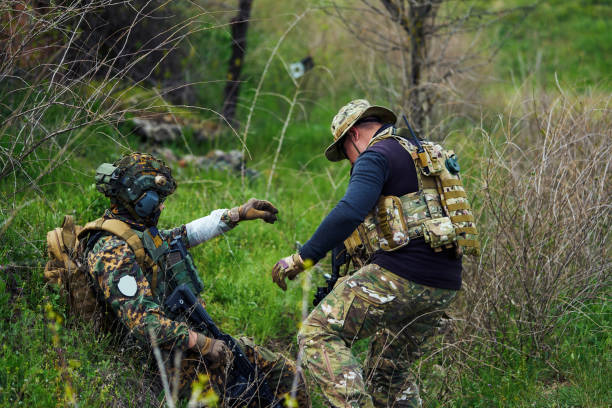 солдат перевязал раненую руку военнослужащему повязкой - hunting two people camouflage rifle стоковые фото и изображения