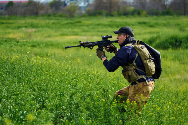 jogador de airsoft em uniforme militar tem uma arma em suas mãos - conciliator - fotografias e filmes do acervo