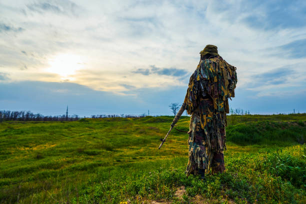 um atirador de uniforme militar camuflado tem um rifle nas mãos. - conciliator - fotografias e filmes do acervo