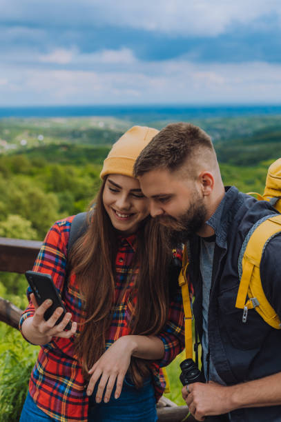 istock Hikers taking a selfie with a smartphone while standing on a lookout with camping gear 1318032122