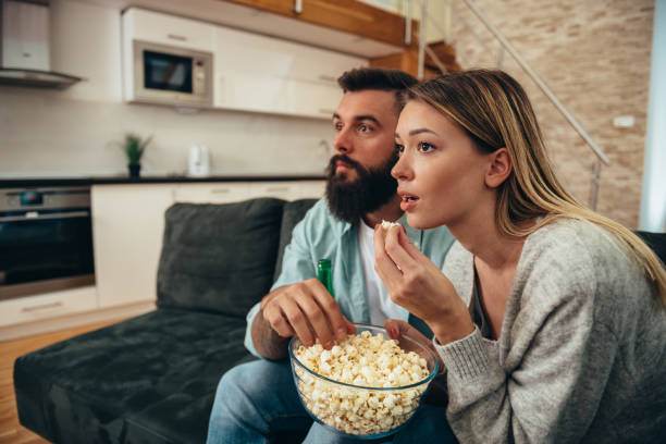 istock Couple drinking beer and popcorn while watching sport game at home 1318032136