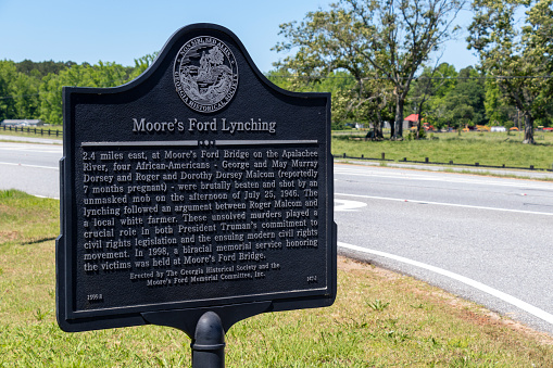 Monroe, Georgia - May 14, 2021: Close-up of the historical marker pointing to the site of the lynching of four African Americans by an unmasked mob on July 25, 1946, near the Moore's Ford Bridge in Walton County, about 60 miles east of Atlanta. The unsolved murders are considered to have been the last mass-lynching in the United States.
