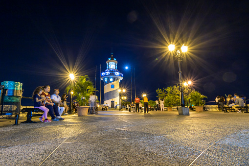 The lighthouse at the top of the Santa Ana hill and the in the city of Guayaquil, with visitors at night.