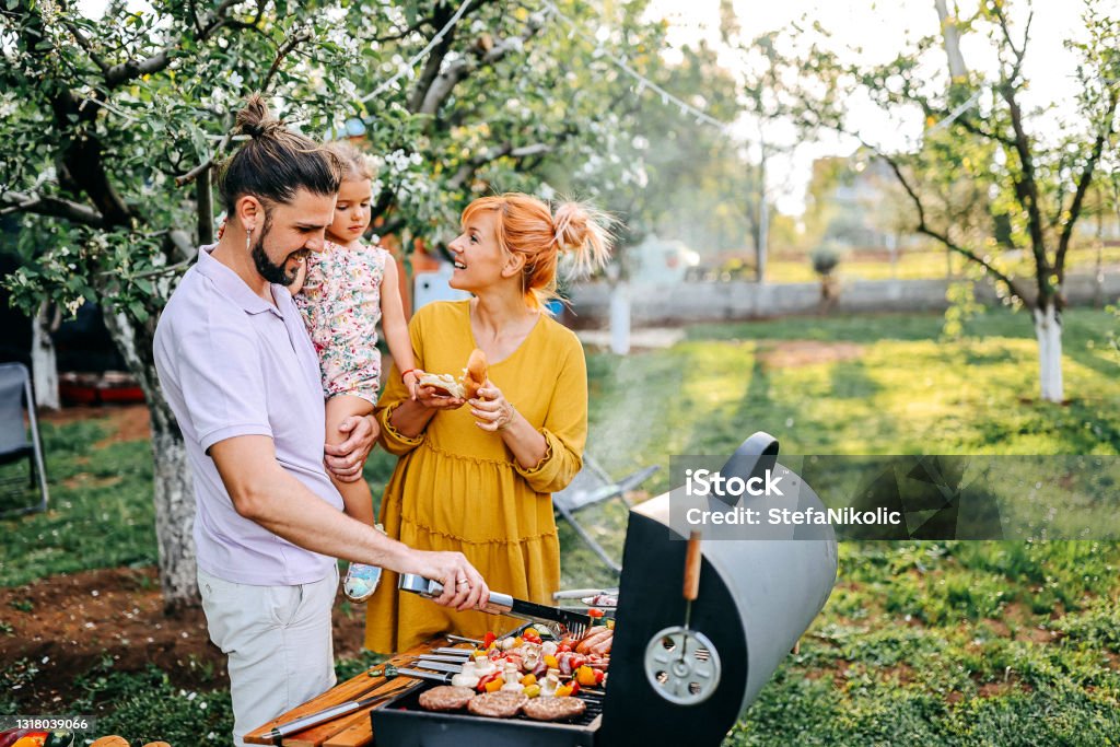 Nice and fresh Family preparing meal in backyard on barbecue grill Barbecue - Meal Stock Photo