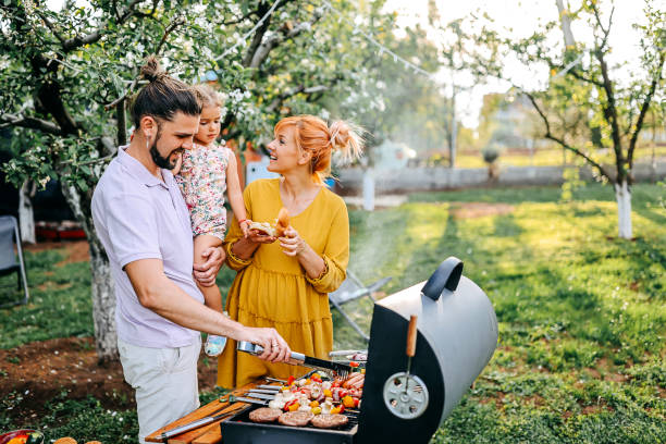 Nice and fresh Family preparing meal in backyard on barbecue grill barbecue grill stock pictures, royalty-free photos & images