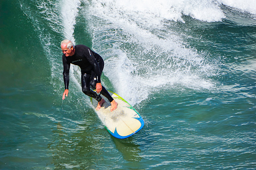 Huntington Beach, CA - May 14, 2021: Senior man surfing off of California coast