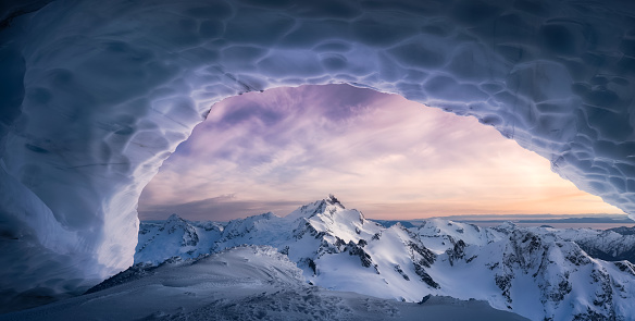 Magical Winter Mountain Landscape Composite viewed from inside the Ice Cave. Colorful Sunset Sky Art Render. Background taken from British Columbia, Canada.